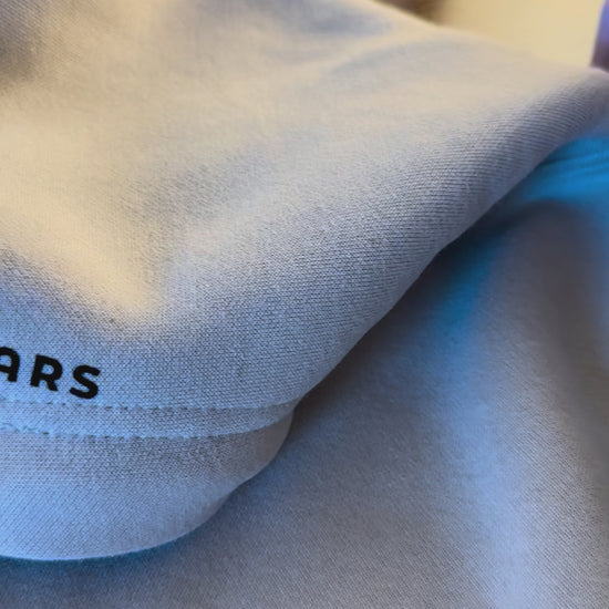 Close-up of beige minimalist streetwear hoodie with Urdu poetry sleeve print, engineered for permanence.
