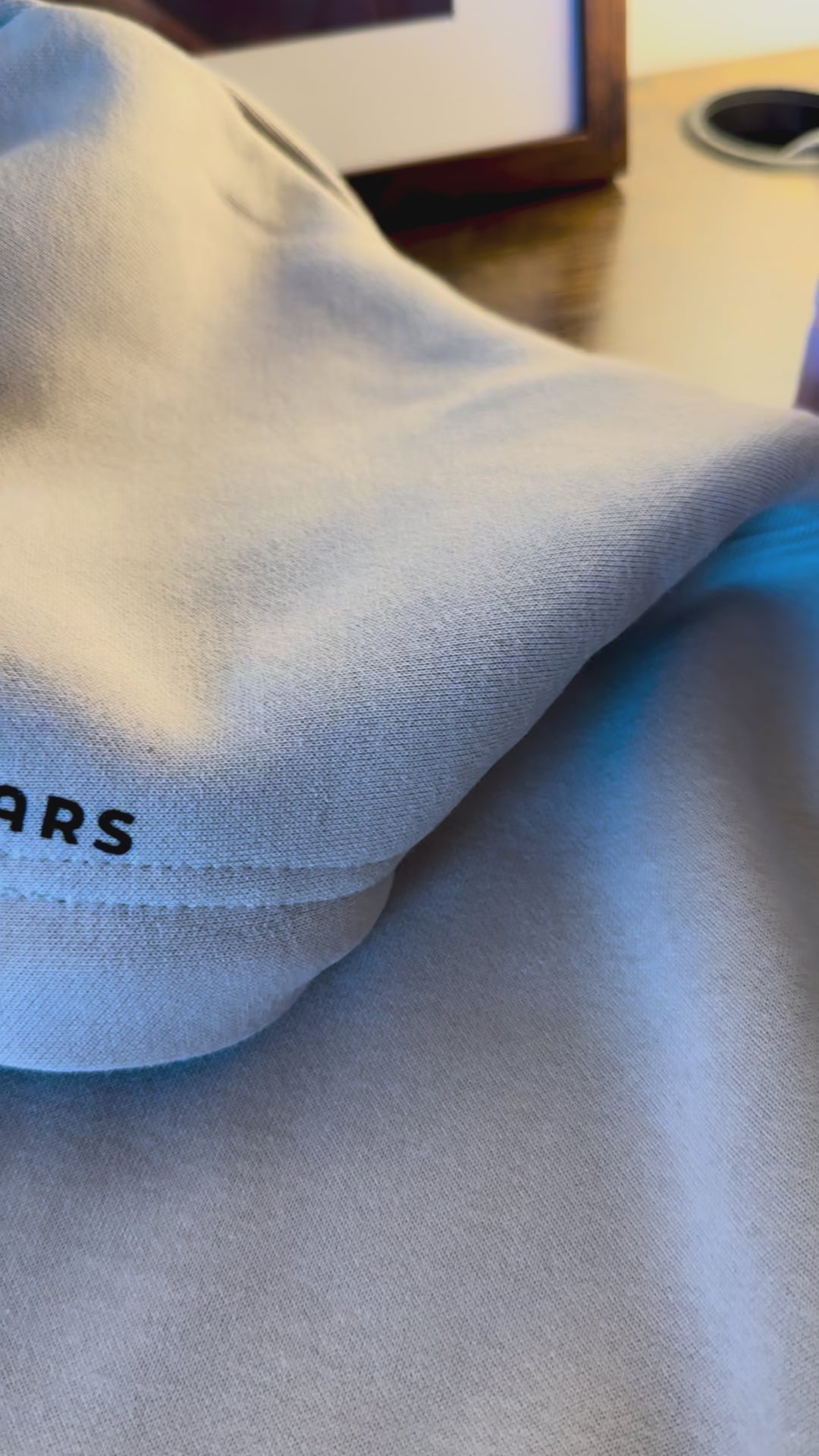 Close-up of beige minimalist streetwear hoodie with Urdu poetry sleeve print, engineered for permanence.